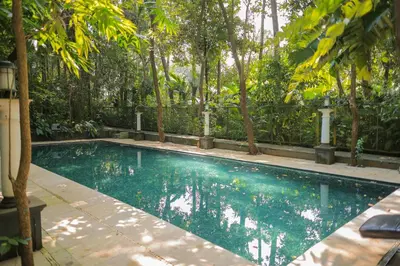 a swimming pool in a garden with trees at Softouch Ayurveda Village Kerala in Kizhake Chālakudi