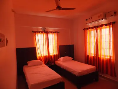 two beds in a room with red curtains at KV Residency in Coimbatore