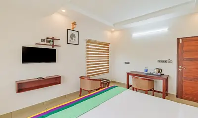 a bedroom with a bed and a desk and a tv at Treebo Amigos Residency in Cochin