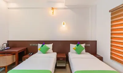 a hotel room with two beds and a desk at Treebo Amigos Residency in Cochin