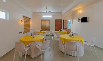 a dining room with yellow tables and white chairs at Treebo Amigos Residency in Cochin