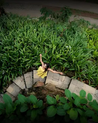 a woman in a yellow dress in a field of plants at Willow Resorts Wayanad in Ambalavayal
