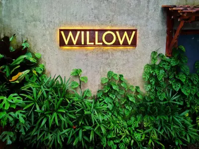 a sign on the side of a wall with plants at Willow Resorts Wayanad in Ambalavayal