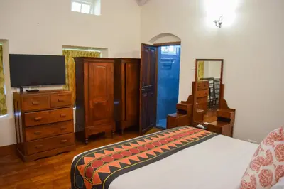 a bedroom with a bed and a dresser and a tv at Ibex Resorts, Coonoor Leewood in Coonoor