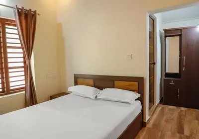 a bedroom with a bed with white sheets and a window at CELESTIAL HOMESTAY in Pinangode