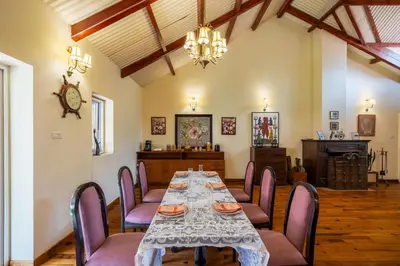 a dining room with a table and chairs and a clock at amã Stays & Trails Raven's Nest , Kotagiri in Kotagiri