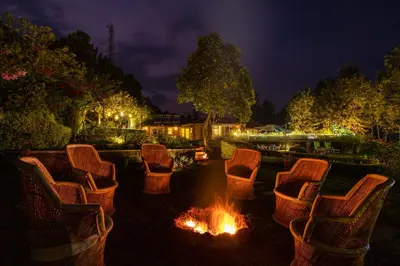 a group of chairs around a fire pit at night at amã Stays & Trails Raven's Nest , Kotagiri in Kotagiri