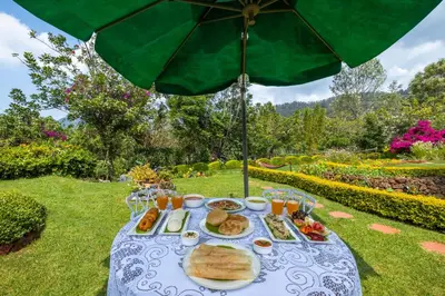 a table with a plate of food and an umbrella at amã Stays & Trails Raven's Nest , Kotagiri in Kotagiri