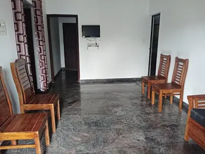 a room with three wooden chairs and a basketball hoop at BHASURI SERVICED VILLA in Varagampadi