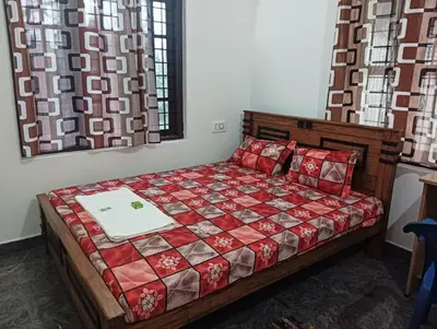 a bedroom with a bed with a red quilt at BHASURI SERVICED VILLA in Varagampadi