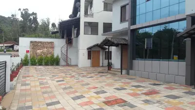 a building with a tiled courtyard in front of it at Woodstock Resorts in Madikeri