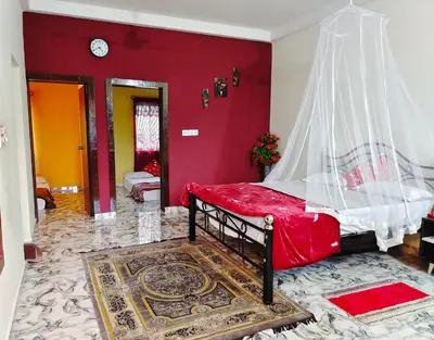 a bedroom with a bed with a red wall at Mannat Inn Homestay (Mysore) in Mysore
