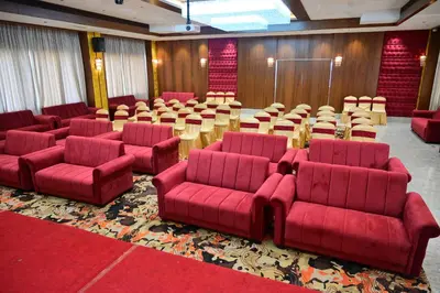 a room with red chairs and tables in a room at Hotel Golden Riviera in Mysore