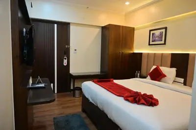 a bedroom with a bed with a red blanket on it at Hotel Golden Riviera in Mysore