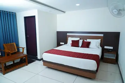 a bedroom with a large bed and a chair at Rainbow Inn in Munnar