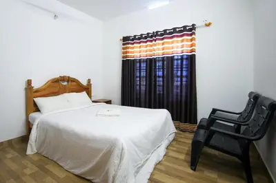 a bedroom with a bed and a chair and a window at B'camp Resorts & Homestays in Wayanad