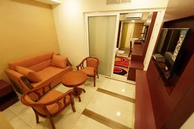 a living room with a couch and chairs and a television at Hotel Newline Orchid in Guruvāyūr