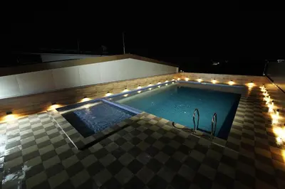 a swimming pool with lights on a building at night at Hotel Newline Orchid in Guruvāyūr