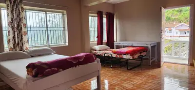 a bedroom with two beds and a table and windows at Heath Cote in Ooty