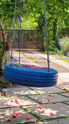 a tire swing in a park with flowers on the ground at Nostalgia Homestay in Vythiri