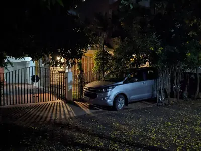 a car parked in front of a fence at night at Athreyas@60/A in Mysore