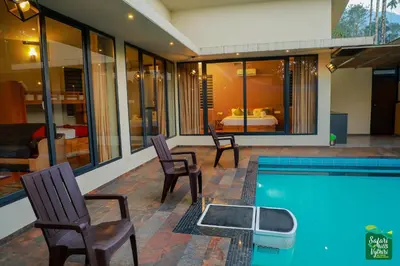 a house with a pool and two chairs and a bedroom at Safari Hills in Vayittiri