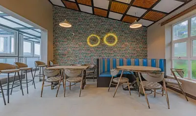 a restaurant with tables and chairs and a brick wall at Treebo Windsor Heights, 8 Mins To Ketti Valley View Point in Ooty