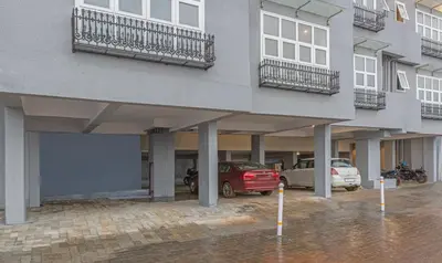 a building with cars parked in a parking lot at Treebo Windsor Heights, 8 Mins To Ketti Valley View Point in Ooty