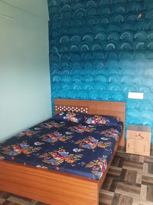 a bedroom with a bed with a blue wall at Paadi Inn in Kakkabe