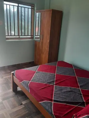 a bedroom with a red and black quilt on a bed at Paadi Inn in Kakkabe