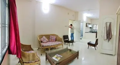 a man is standing in a living room at Raintree Garden in Mysore