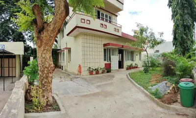a building with a tree in front of it at Raintree Garden in Mysore