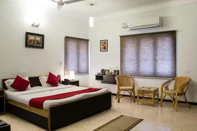 a bedroom with a bed with red pillows and chairs at Corner Stay Serviced Apartment-Racecourse in Coimbatore
