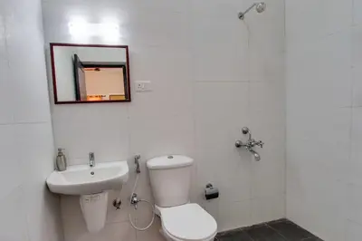 a bathroom with a toilet and a sink and a mirror at Corner Stay Serviced Apartment-Racecourse in Coimbatore