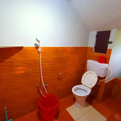 a bathroom with a toilet and a red bucket at Kalpetta Peace Villa in Kalpetta