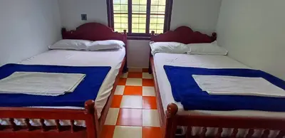 two twin beds in a room with a window at Kalpetta Peace Villa in Kalpetta