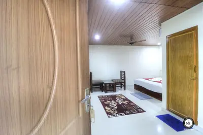 a room with a door and a bedroom with a bed at Coorg Avani Holiday Inn in Madikeri