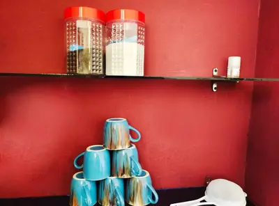 a shelf with cups and books on a red wall at Mannat Inn (Peace Homestay) in Mysore