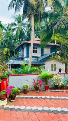 a house with palm trees and flowers in front of it at Namasthe Inn AC, Ottapalam-Palakkad Highway, Lakkidi in Ottappālam