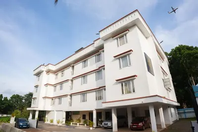 a large white building with a plane in the sky at Daffodils Luxury Airport Suites in Cochin