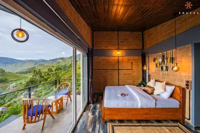 a bedroom with a bed and a balcony at Zostel Plus Poombarai, Kodaikanal in Kodaikānāl