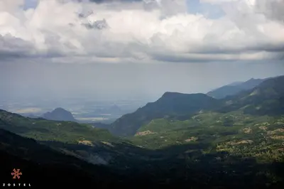 a view of a valley with mountains in the distance at Zostel Plus Poombarai, Kodaikanal in Kodaikānāl