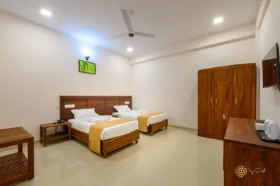 a bedroom with two beds and a tv in it at Daffodils Luxury Airport Suites in Angamali