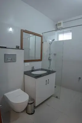 a bathroom with a toilet and a sink and a shower at Daffodils Luxury Airport Suites in Angamali