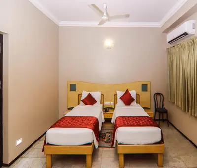 a bedroom with two beds and a ceiling fan at Hotel Vinayaga Excellenciy Tiruppur in Tiruppūr