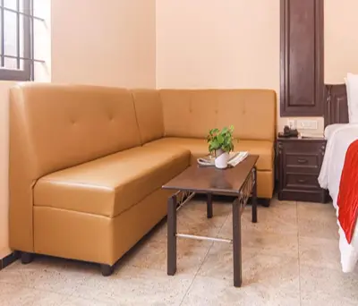 a brown couch in a room with a coffee table at Hotel Vinayaga Excellenciy Tiruppur in Tiruppūr