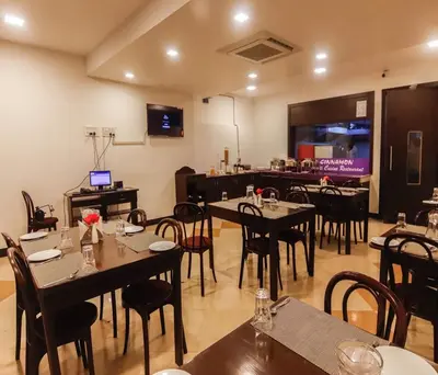 a dining room with tables and chairs and a television at Hotel Vinayaga Excellenciy Tiruppur in Tiruppūr