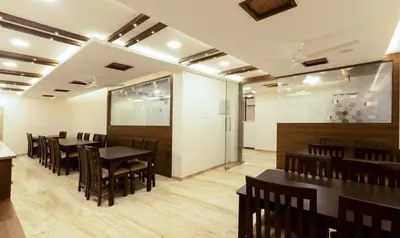 a restaurant with black tables and chairs and a white wall at The Bee Hives , Nectar Nest in Coimbatore