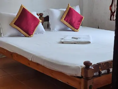 a bed with two pillows and a towel on it at Cicily Cottage in Munnar