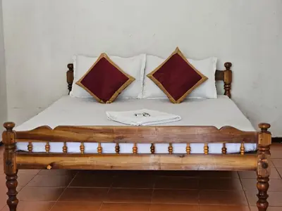 a wooden bed with two pillows on top of it at Cicily Cottage in Munnar